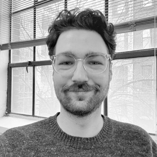 black and white photo of man with glasses smiling