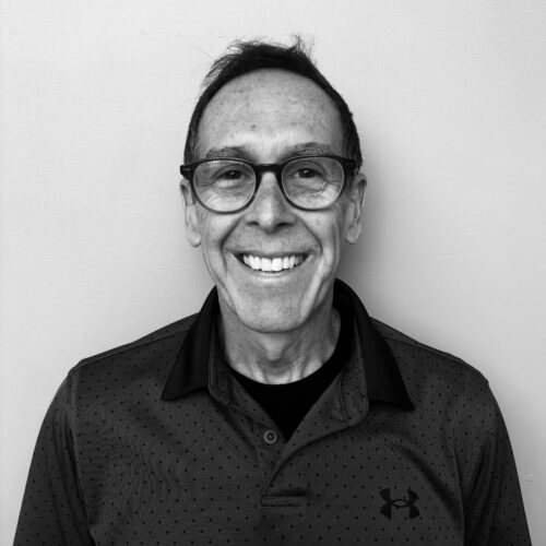 black and white photo of a man with glasses smiling
