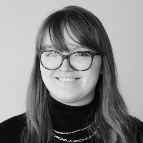 black and white portrait of woman with glasses smiling: Sophia Lefew