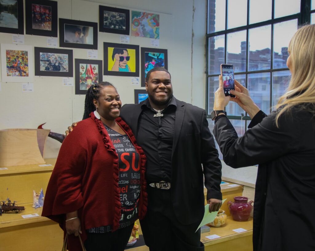 two well dressed people posing for a photo in front of artwork