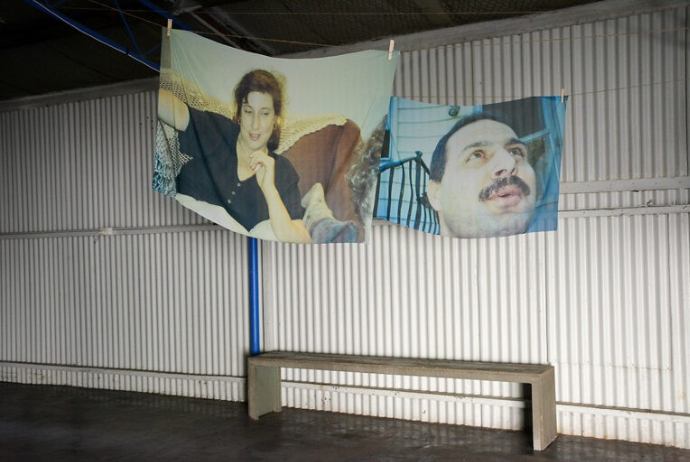 Printed pictures on fabric hang over a bench.